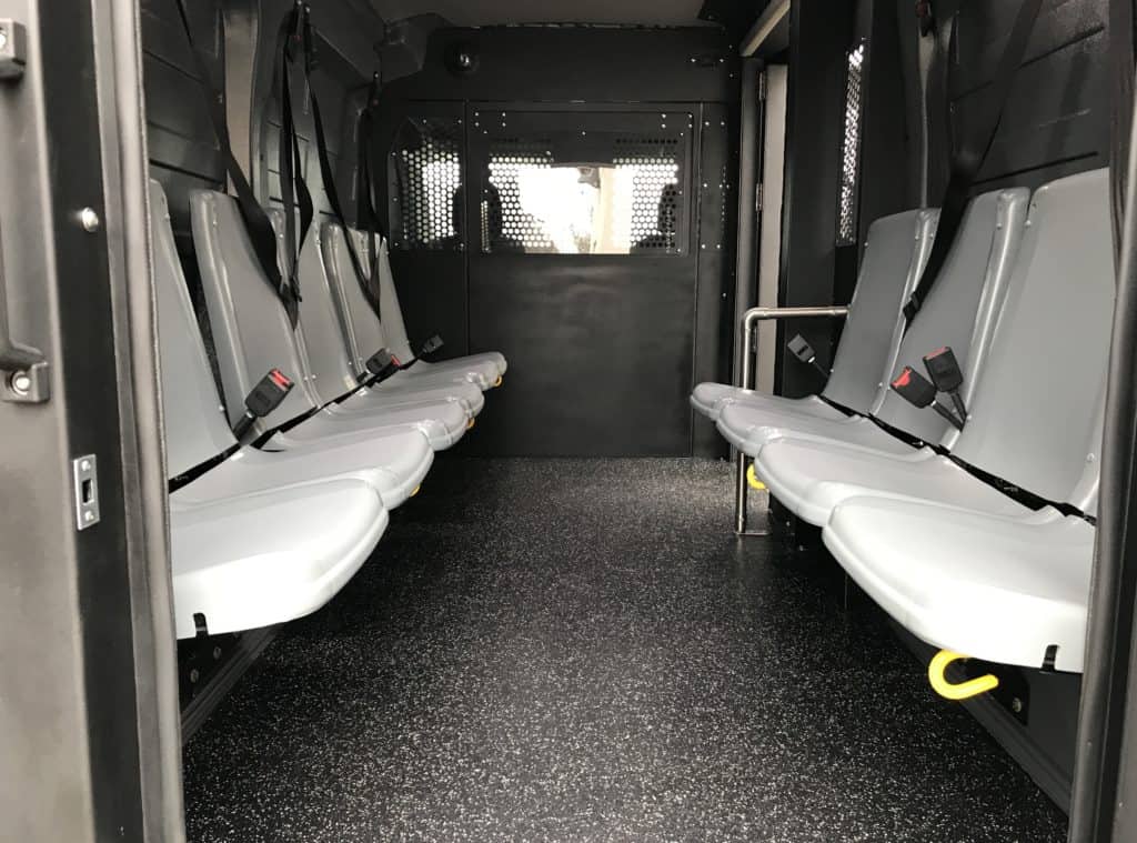 Secure prisoner transport interior with partitioned passenger seating and seat belts